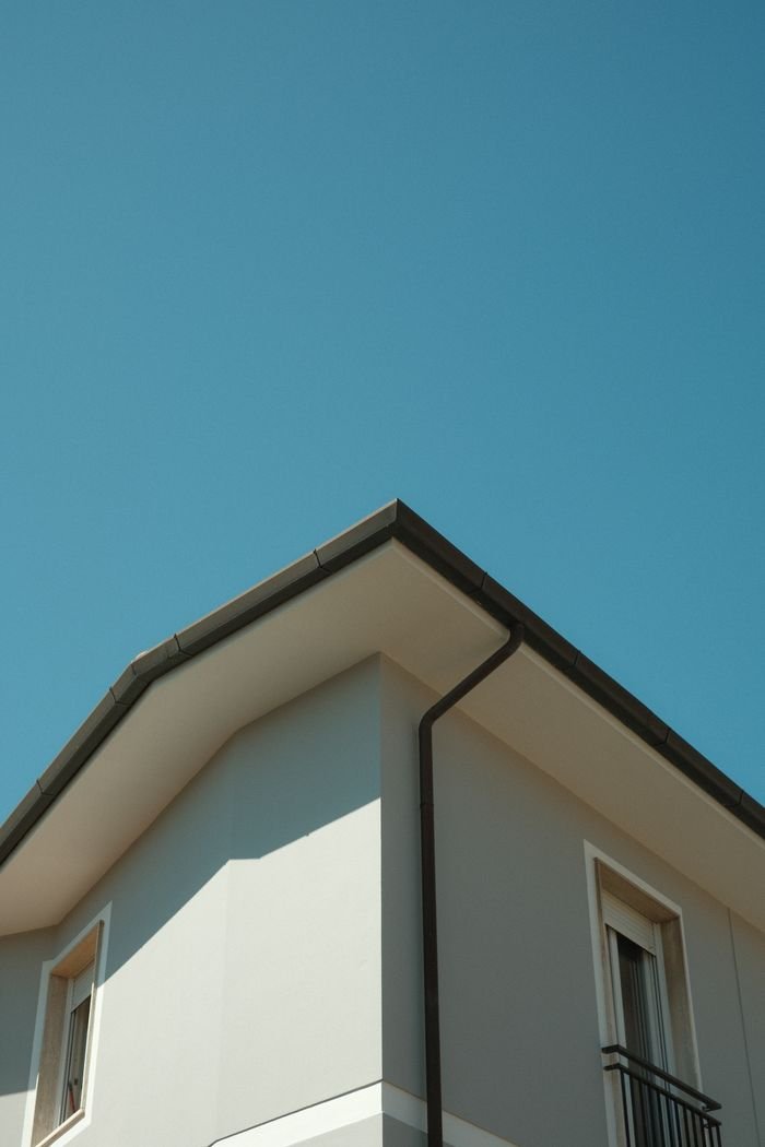 service-01 Contemporary house with a sloped roof against a clear blue sky, showcasing modern architecture.