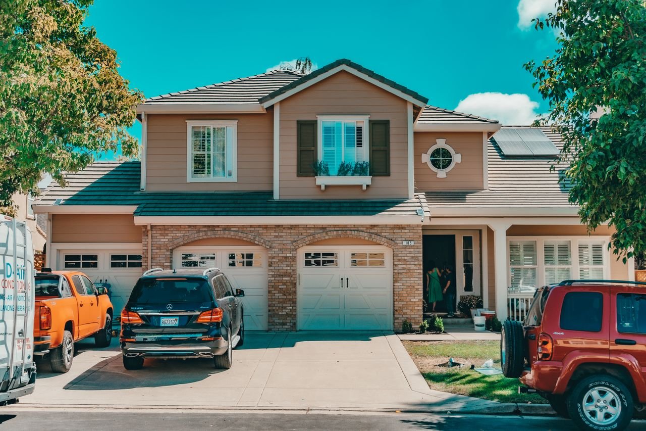 Charming suburban house with parked cars and vibrant summer setting.